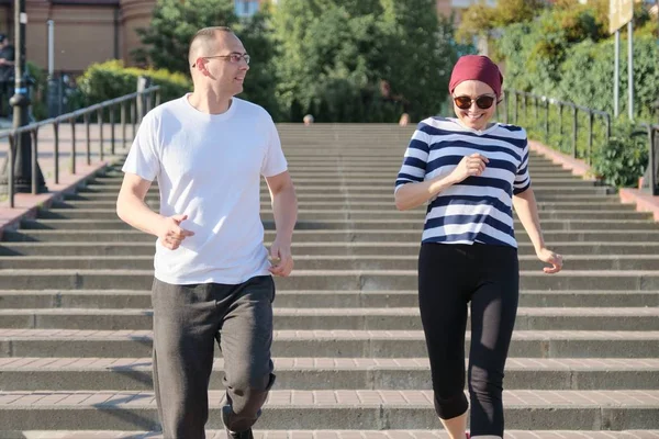 Retrato al aire libre de pareja madura corriendo. Hombre y mujer de 40 años subiendo las escaleras . —  Fotos de Stock