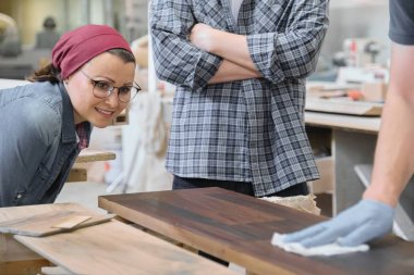 Woodworking workshop, worker varnishing wooden shelf closeup