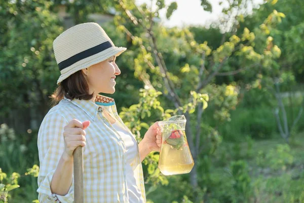 Mulher sorridente com jarro de bebida caseira natural refrescante no jardim de verão — Fotografia de Stock