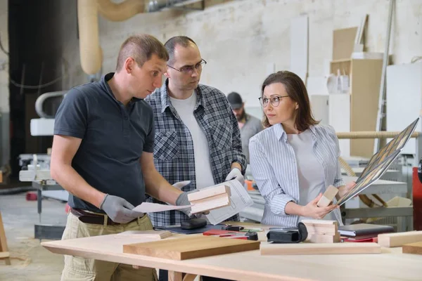 Group of industrial people client, designer or engineer and workers working together on project of wooden furniture.