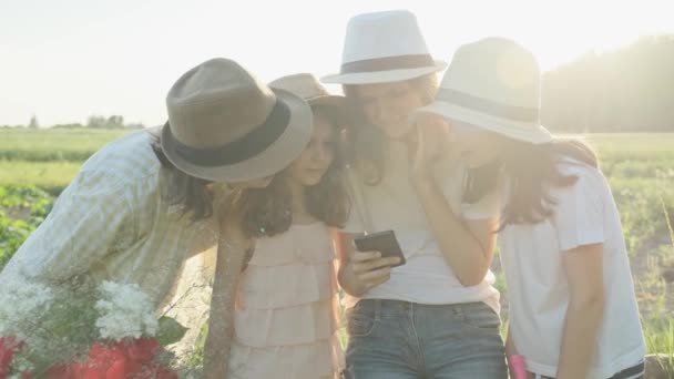 Boldog anya, három lánya keresi a smartphone, a család a természetben — Stock videók