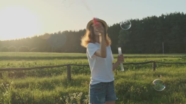 Красива дівчина підліток в капелюсі дме мильні бульбашки — стокове відео