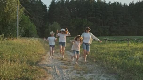 快乐的母亲和三个女儿沿着乡间小路奔跑 夏天的自然背景 黄金时间 — 图库视频影像