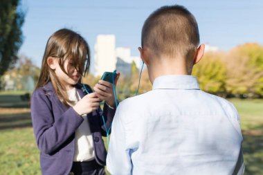 Akıllı telefonlar, sırt çantaları, açık arka plan ile ilköğretim çağındaki çocuklar.