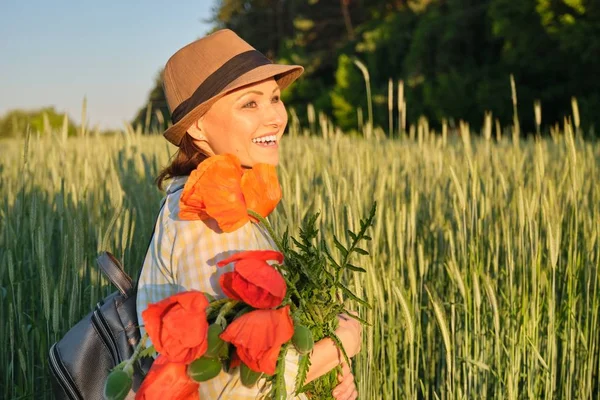 Ritratto all'aperto di una donna matura felice con mazzi di fiori di papaveri rossi . — Foto Stock