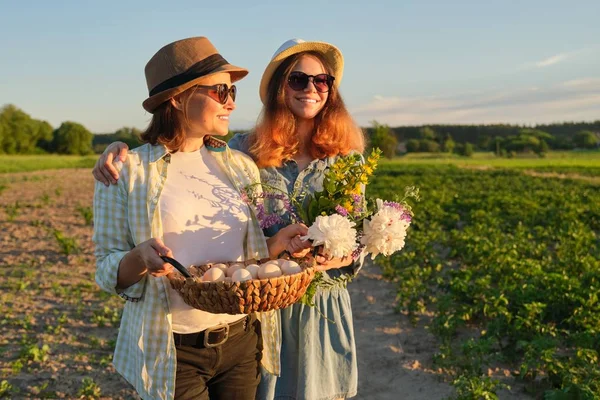 Mor och Tonåring dotter med en korg med färska ägg i trädgården, gyllene timmen — Stockfoto