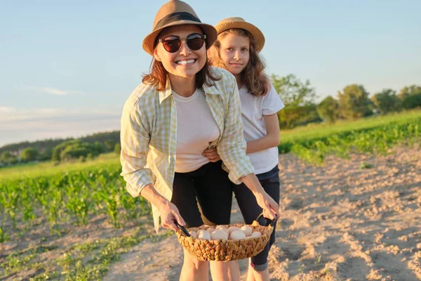 Mor och dotter med en korg med färska ägg i trädgården, gyllene timmen — Stockfoto