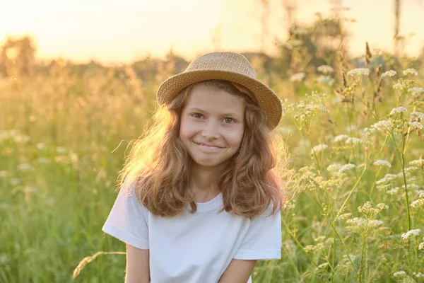 Retrato ao ar livre de uma menina sorridente em um chapéu em um prado ensolarado, hora de ouro — Fotografia de Stock