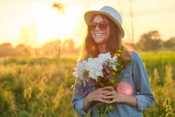 Outdoor portrait of a young girl with flowers on a meadow, golden hour — Stock Photo, Image