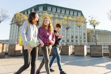 Sırt çantaları ve ders kitapları ile gülümseyen gençler öğrenciler, konuşma ve ileriye gidiyor.