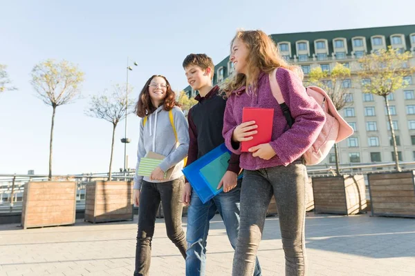 Utendørs portrett av tenåringsstudenter med ryggsekk som går og snakker . – stockfoto