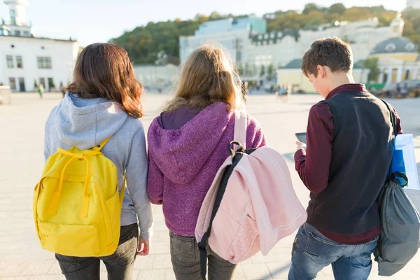 Vista desde atrás de tres estudiantes de secundaria con mochilas — Foto de Stock