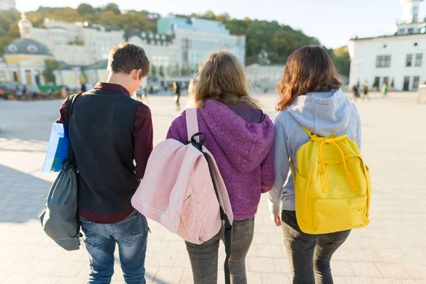 Vista desde atrás de tres estudiantes de secundaria con mochilas . — Foto de Stock