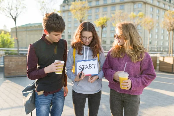 Groep tieners jongen en twee meisjes, met een Kladblok met handgeschreven woord start. — Stockfoto