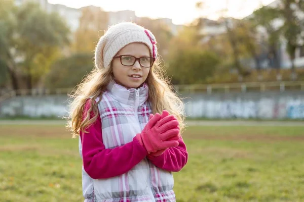 Retrato de una niña feliz 7 años de edad, en un sombrero de punto, gafas, fondo soleado otoño — Foto de Stock