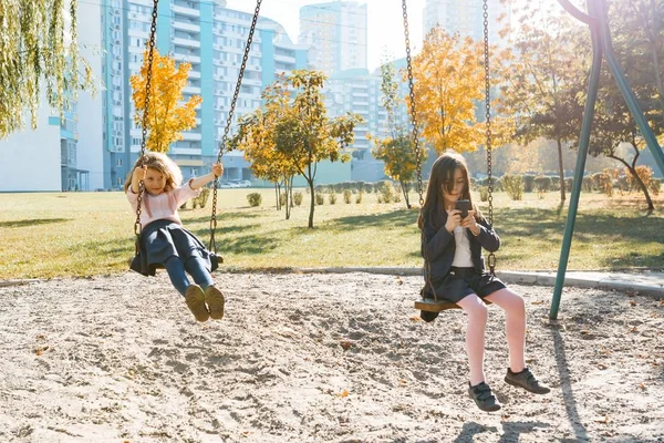 Los niños montan en un columpio en el parque de otoño — Foto de Stock
