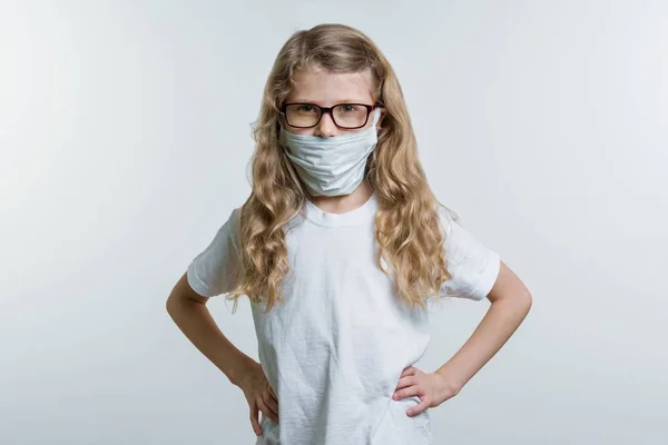 Dziecko dziewczynka w masce medycznej. Na białym tle, w białej bazie T-shirt. — Zdjęcie stockowe