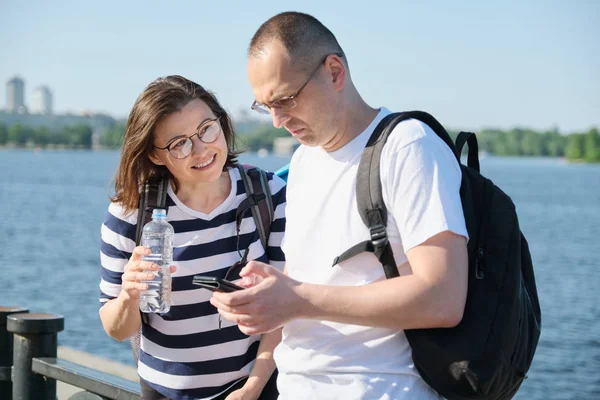 Υπαίθριο ώριμο ζευγάρι χρησιμοποιώντας smartphone, άντρας και γυναίκα που μιλούν WA — Φωτογραφία Αρχείου