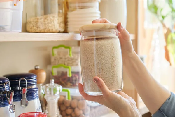 Food products in the kitchen. Woman taking jar of rice — Stock Photo, Image