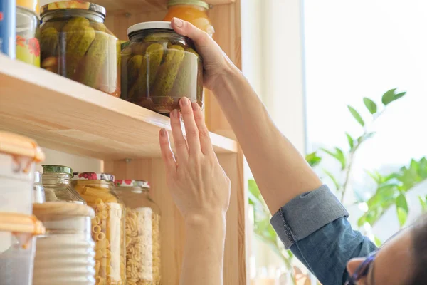 Matvaror i köket, kvinna som tar burk med inlagda gurkor — Stockfoto