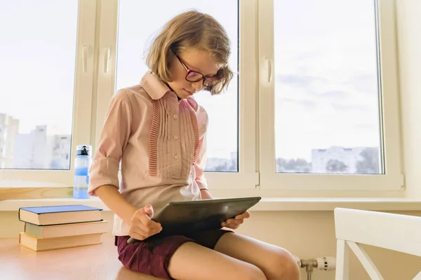 Little schoolgirl uses computer laptop sitting at desk — Stock Photo, Image
