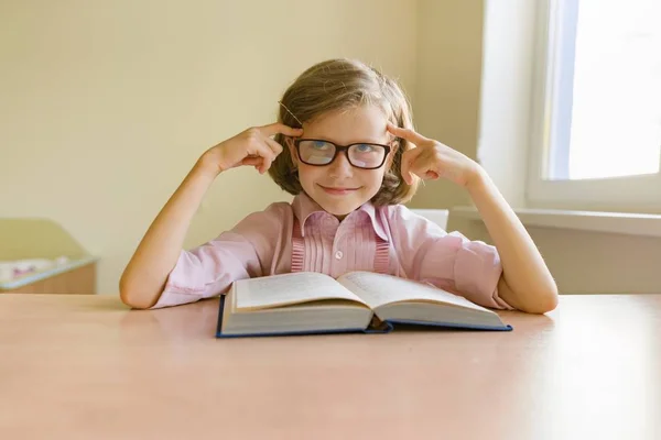 Pequena menina inteligente com óculos lendo grande livro — Fotografia de Stock