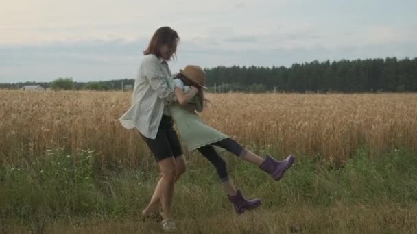 Мать играет со своей дочерью, женщина кружит ребенка в природе — стоковое видео