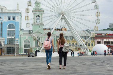 Kiev Ua, 19-07-2018. Genç kızlar şehrin sokaklarında yürüyorlar. Arka plan dönme dolap, Avrupa şehrinin kare, arkadan görünümü