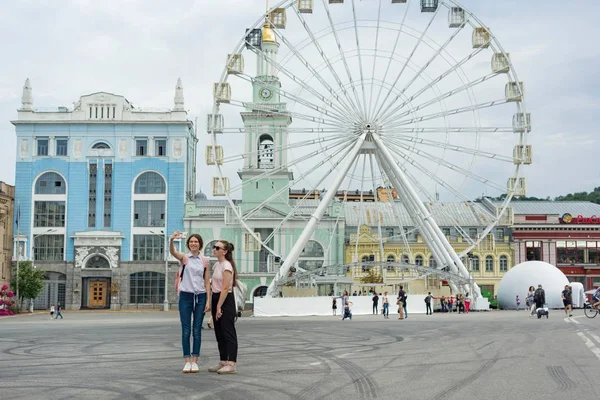 Киев, 19 июля 2018 года. Девочки-подростки ходят по улицам города. Предпосылки / контекст Ferris wheel, square of the European city — стоковое фото