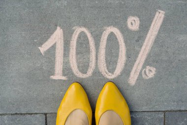 Kadın ayakları ile yüzde 100 gri kaldırımda yazılı metin.