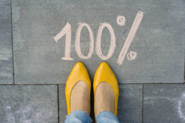 Kadın ayakları ile yüzde 100 gri kaldırımda yazılı metin.