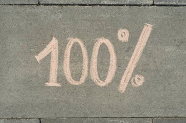 Gri kaldırımda yüzde 100 yazılmış metin.
