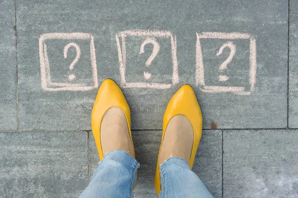 Pés de mulher com 3 pontos de interrogação na frente de suas pernas pintadas na calçada cinza — Fotografia de Stock