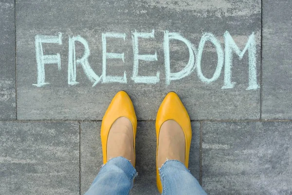 Ženské nohy s textem svoboda napsal na šedém chodníku — Stock fotografie