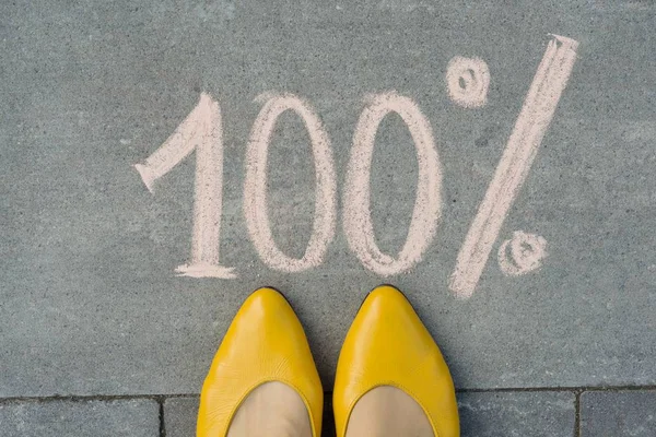Жіночі ноги з текстом 100% написані на сірому тротуарі . — стокове фото