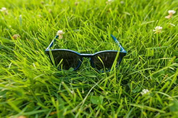 Sunglasses in bright green grass, summer accessory — Stock Photo, Image