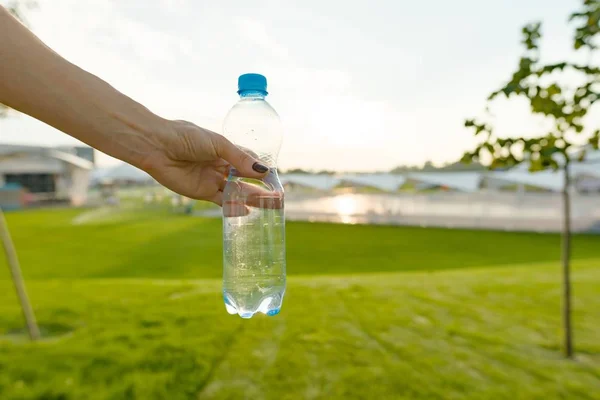 Bottle of water in female hand, copy space