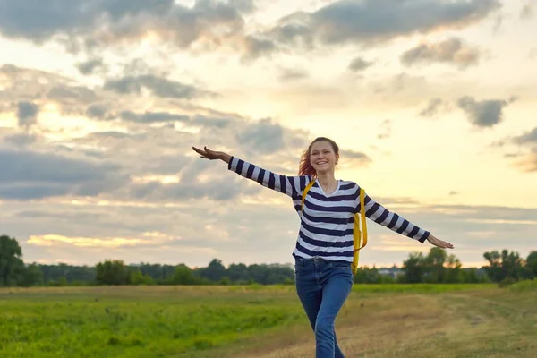 Chica joven corriendo con mochila amarilla, con las manos abiertas —  Fotos de Stock