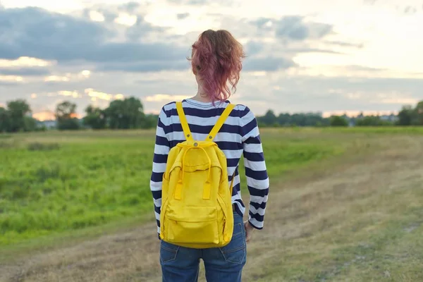 Young girl with yellow backpack, back, , evening sunset sky