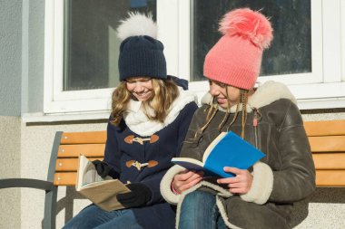 Kitaplar, pozitif insanlar ve dostluk kavramı ile bir bankta neşeli genç arkadaş öğrencilerin Kış portresi.