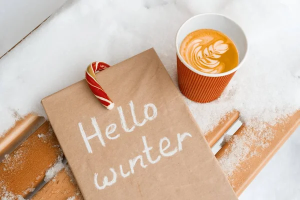 Hola invierno, fondo nevado, cañas de Navidad candi, taza de café, libro de invierno — Foto de Stock