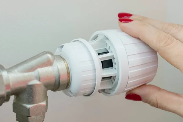 Verwarming radiator in een appartement. De vrouwelijke hand op de thermostaat regelt de temperatuur. — Stockfoto