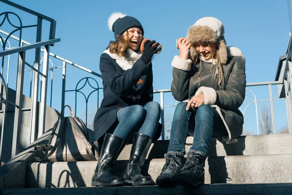 Girls teens shout into a megaphone paper cup, dressed in winter — Stock Photo, Image