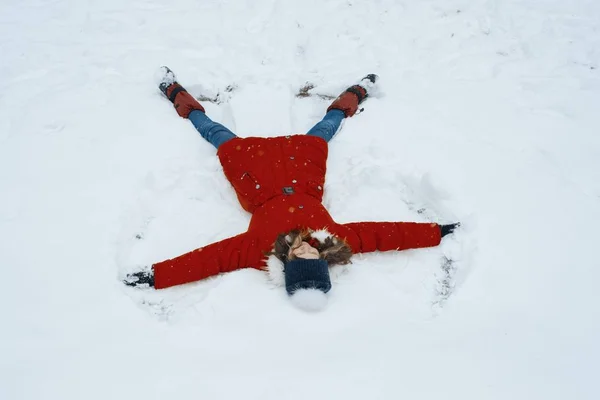 천사의 형태로 눈 위에 누워, 눈 속에서 재미를 쾌활한 소녀의 겨울 초상화, 상단보기 — 스톡 사진