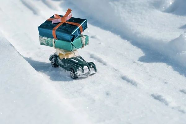 Jouet extérieur vintage voiture rétro avec des cadeaux pour Noël et le Nouvel An, voiture sur une route enneigée. Journée d'hiver ensoleillée et givrée, beaucoup de neige — Photo