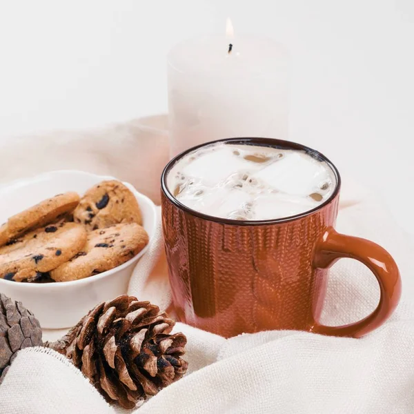 Boisson chaude traditionnelle de Noël cacao avec guimauve et biscuits avec des gouttes de chocolat en tasse rouge, cônes, bougie . — Photo