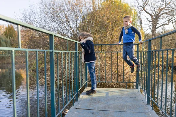 Copii băiat și fată în picioare pe pod, uitându-se la rațe — Fotografie, imagine de stoc