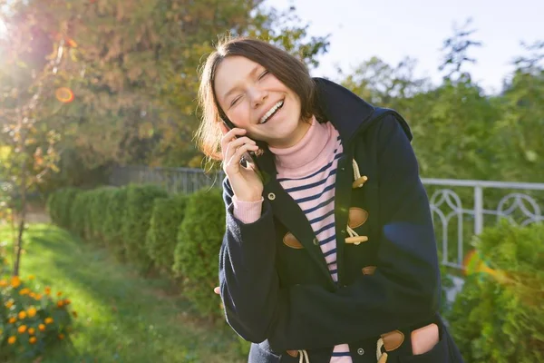 Cep telefonu yla konuşan paltolu mutlu gülümseyen genç kız — Stok fotoğraf