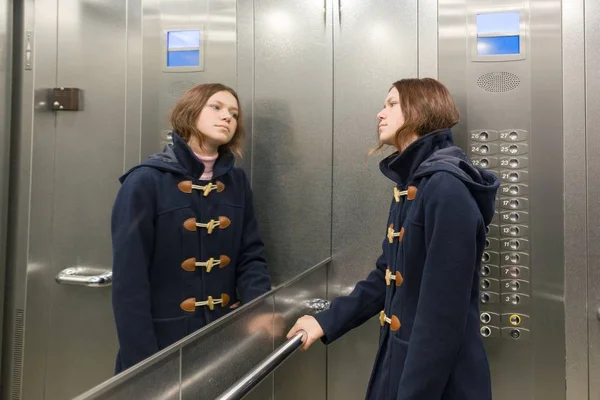 Adolescente de pé no elevador, olhando no espelho — Fotografia de Stock
