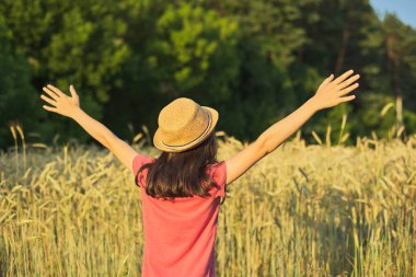 Açık elleriyle sırtlarıyla buğday tarlasında şapkalı kız